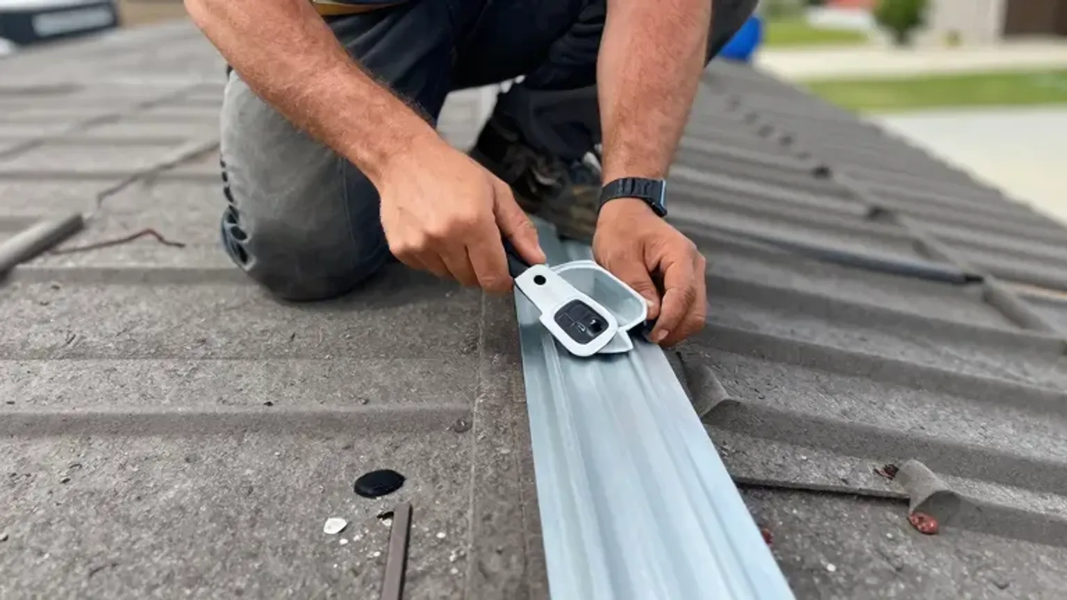Documentary-style iPhone photo of a roof technician resealing flashing detail during routine maintenance in Saratoga Springs, Utah. Natural light.