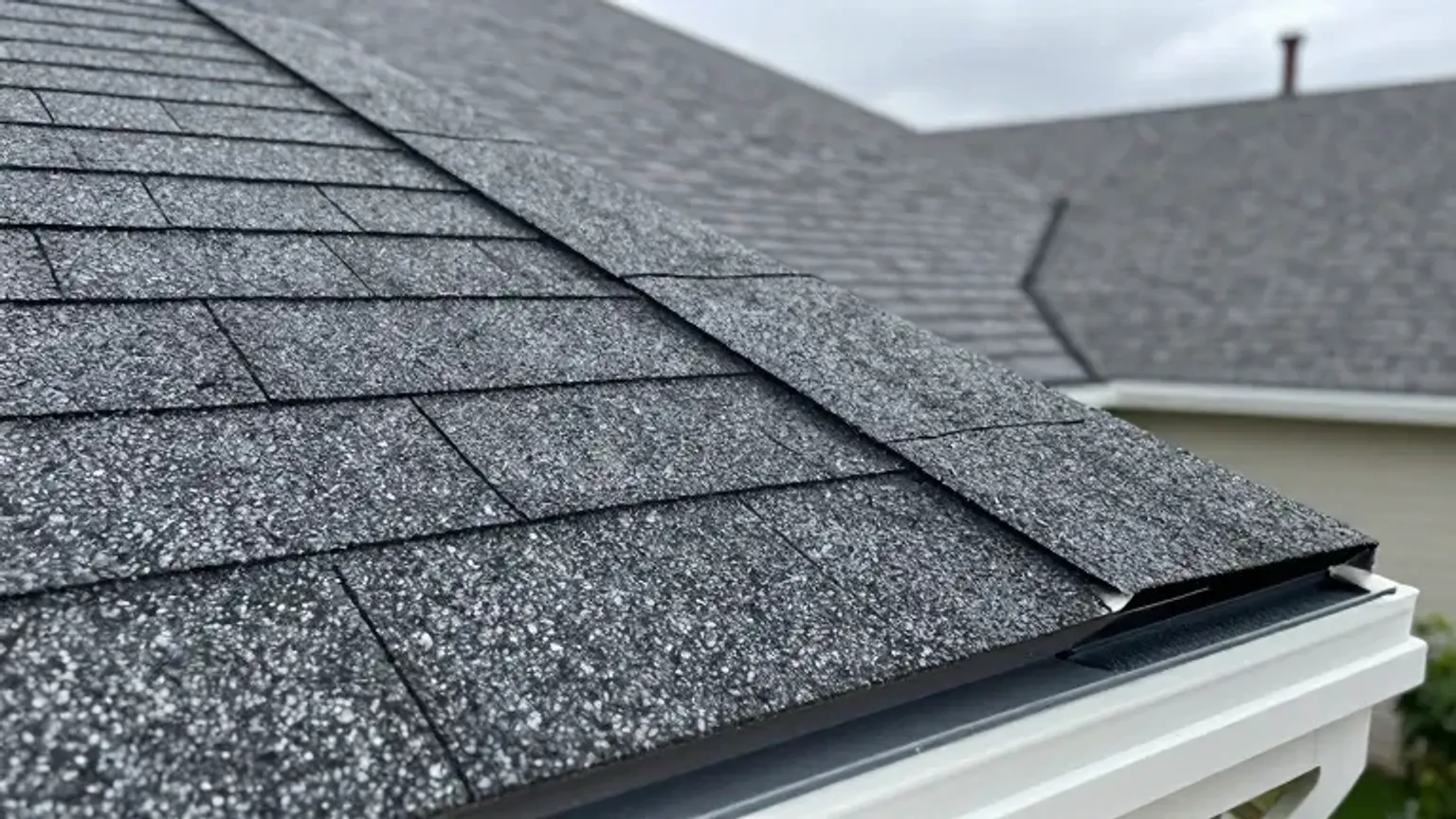 Documentary-style iPhone close-up of architectural asphalt shingles on a residential home in Saratoga Springs, Utah. Natural lighting.