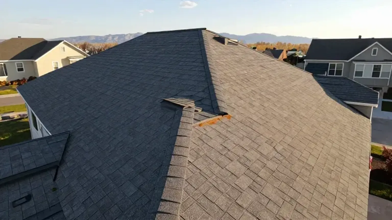 Documentary-style iPhone photo of completed shingle replacement with clean finished roofline on a home in Saratoga Springs, Utah. Natural afternoon light.