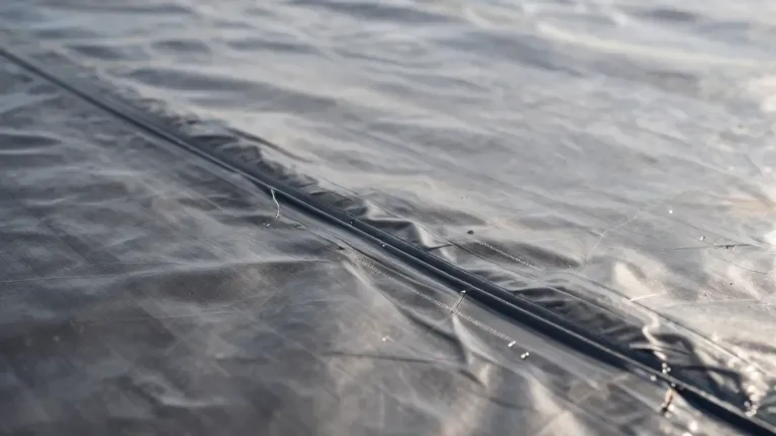 Documentary-style iPhone close-up of flat roof seam repair and heat-welded membrane detail in Saratoga Springs, Utah. Natural lighting.