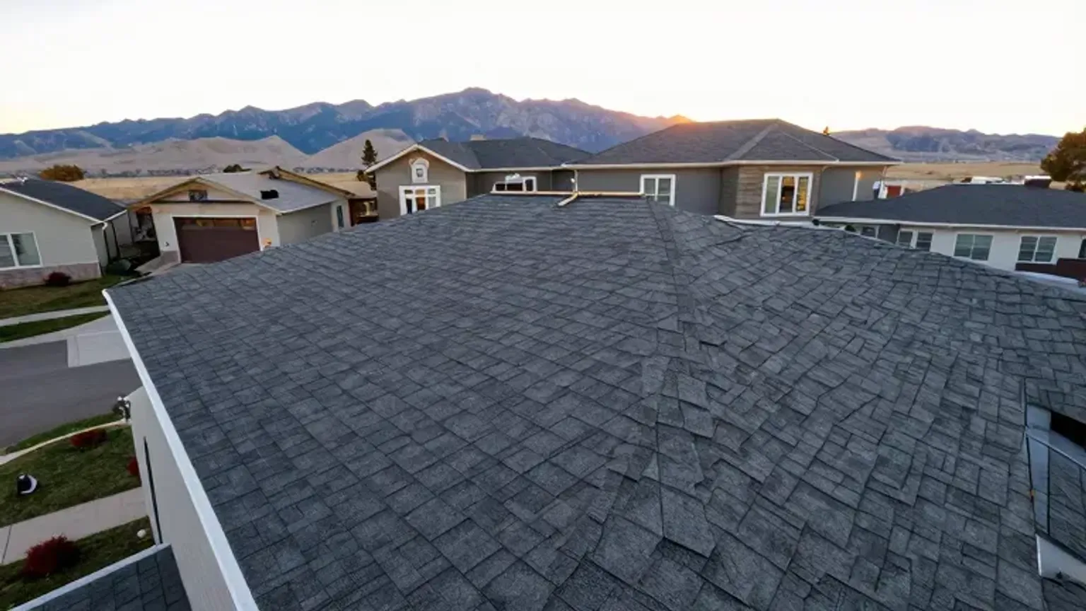 Documentary-style iPhone photo of a completed residential roof replacement in Saratoga Springs, Utah with clean shingle lines and flashing details. Natural daylight.